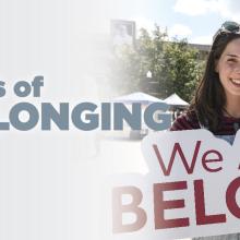 Woman holding a sign that reads "We All Belong"