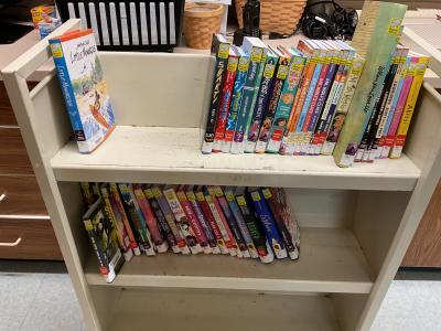 A cart of various books, graphic novels various titles available for student check out. 