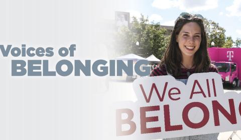 Woman holding a sign that reads "We All Belong"