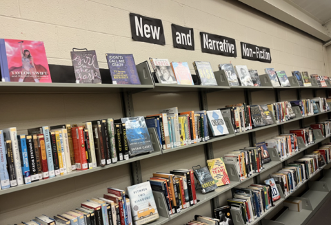 The image shows a display in a library featuring shelves labeled "New and Narrative Non-Fiction." 